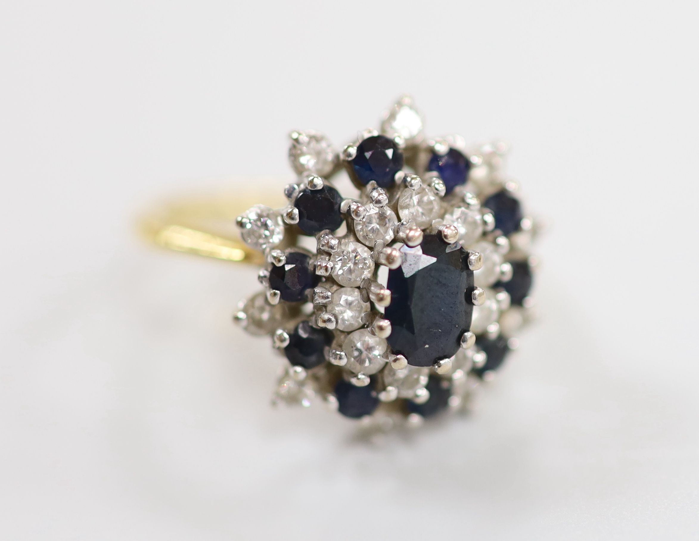 An 18ct yellow metal, sapphire and diamond set oval cluster dress ring, size M, gross weight 6 grams.